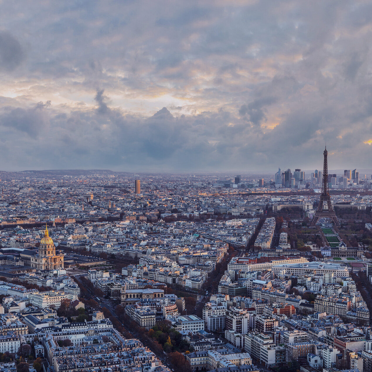 Vue aérienne de Paris au crépuscule avec la Tour Eiffel et le dôme des Invalides visibles, illustrant le paysage urbain dense de la capitale française. Vue aérienne de Paris au crépuscule avec la Tour Eiffel et le dôme des Invalides visibles, illustrant le paysage urbain dense de la capitale française.